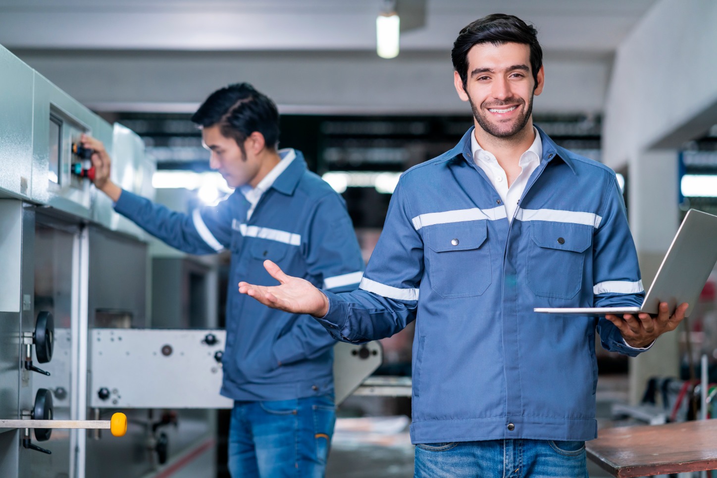 Dos hombres en ropa de trabajo azul al lado de máquinas