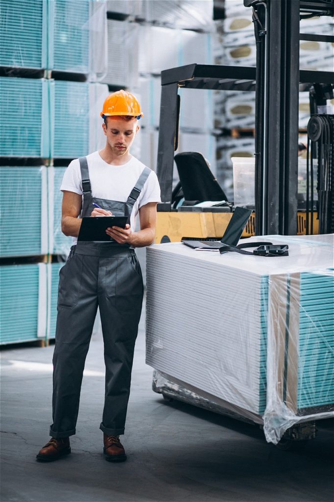 Hombre tomando notas al lado de un montacargas